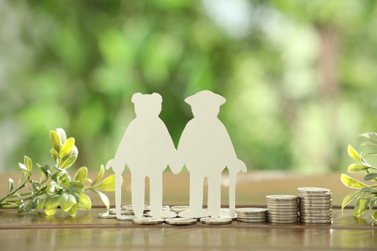 pension-savings-figure-senior-couple-coins-green-twigs-wooden-table-outdoors
